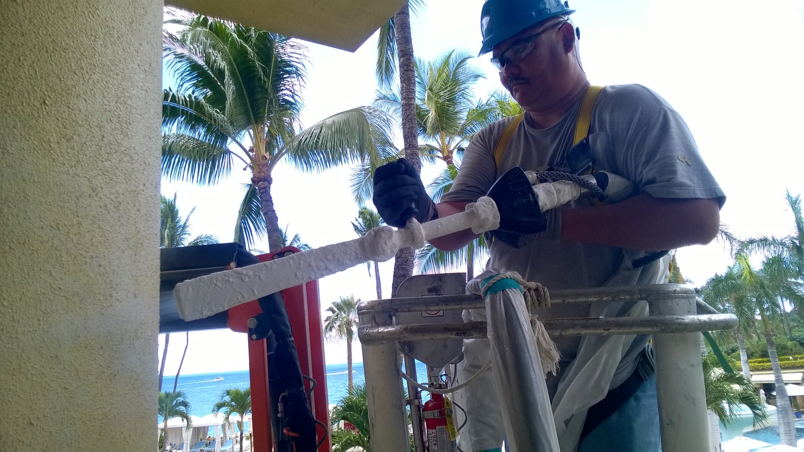 Dibshawaii operator dry ice blasting a resort railing with palm trees and ocean behind